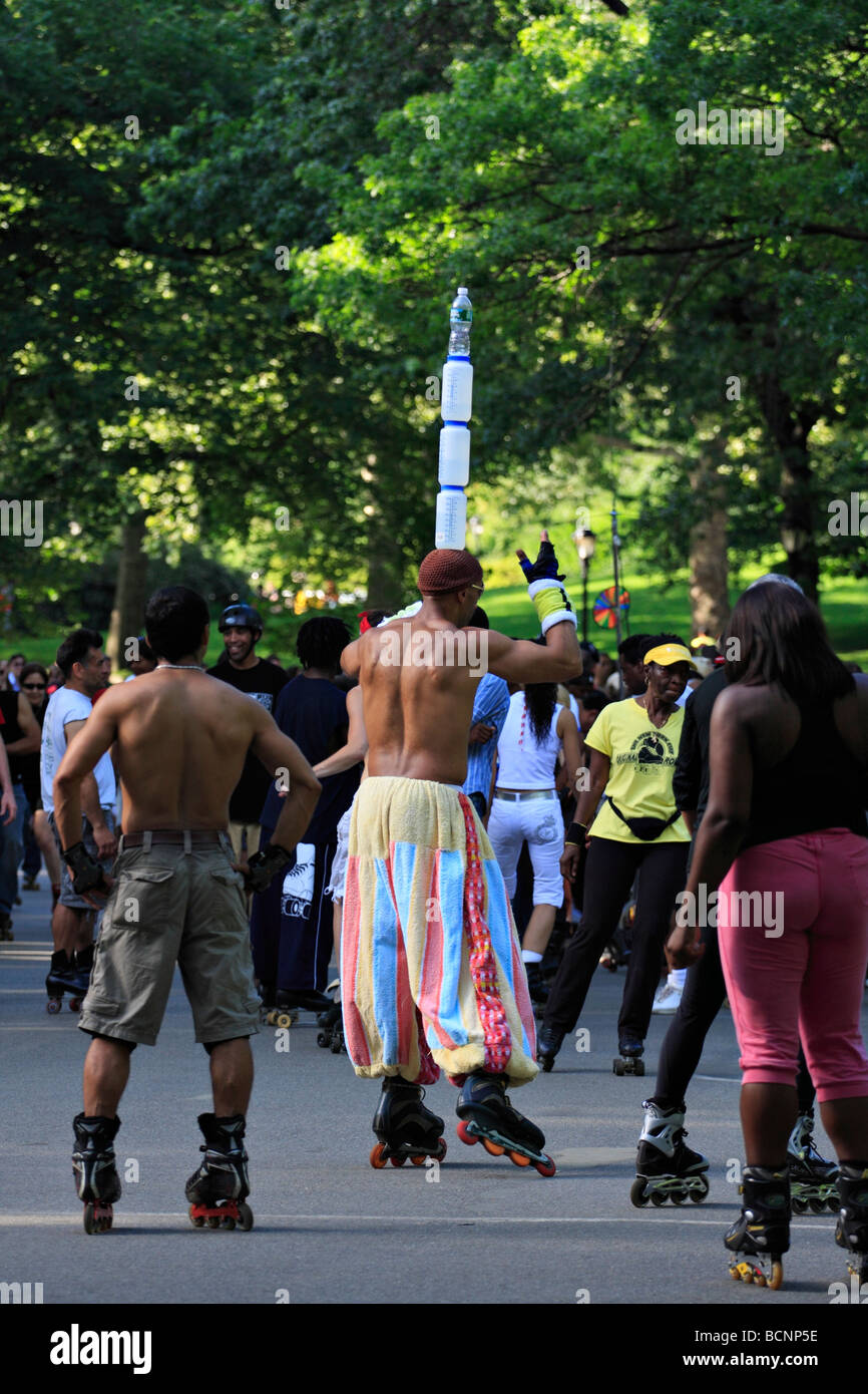 L'homme sur l'équilibrage du roller des bouteilles d'eau sur la tête. Roller Disco dans Central Park à New York. Banque D'Images