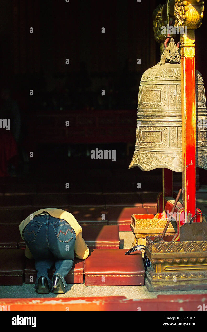 Prière bouddhiste en grande salle de prière à côté d'une cloche de bronze, Temple Fayuan, Beijing, Chine Banque D'Images