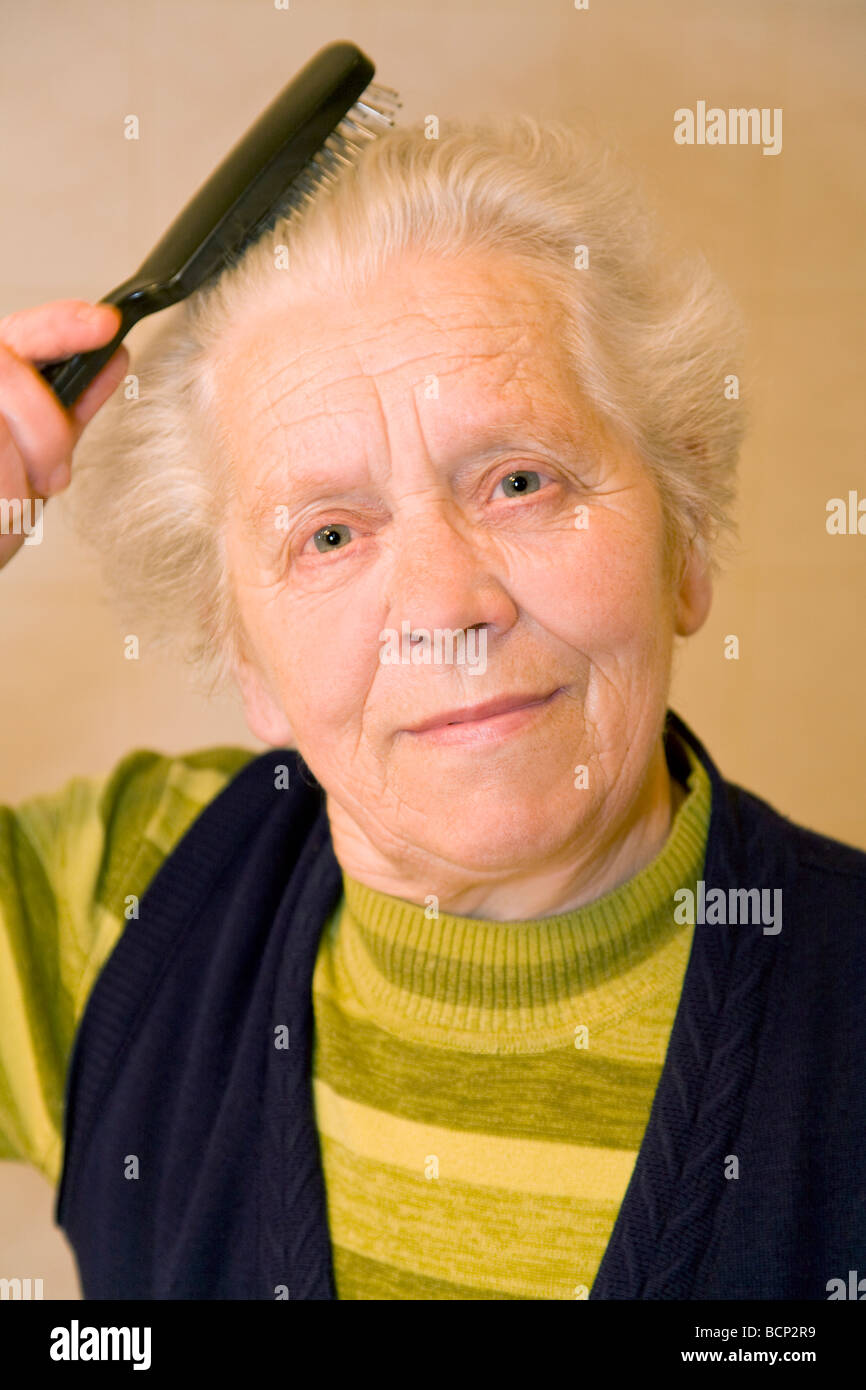 Frau dans Siebzigern bürstet ihren grauen sich ihre Haare Banque D'Images
