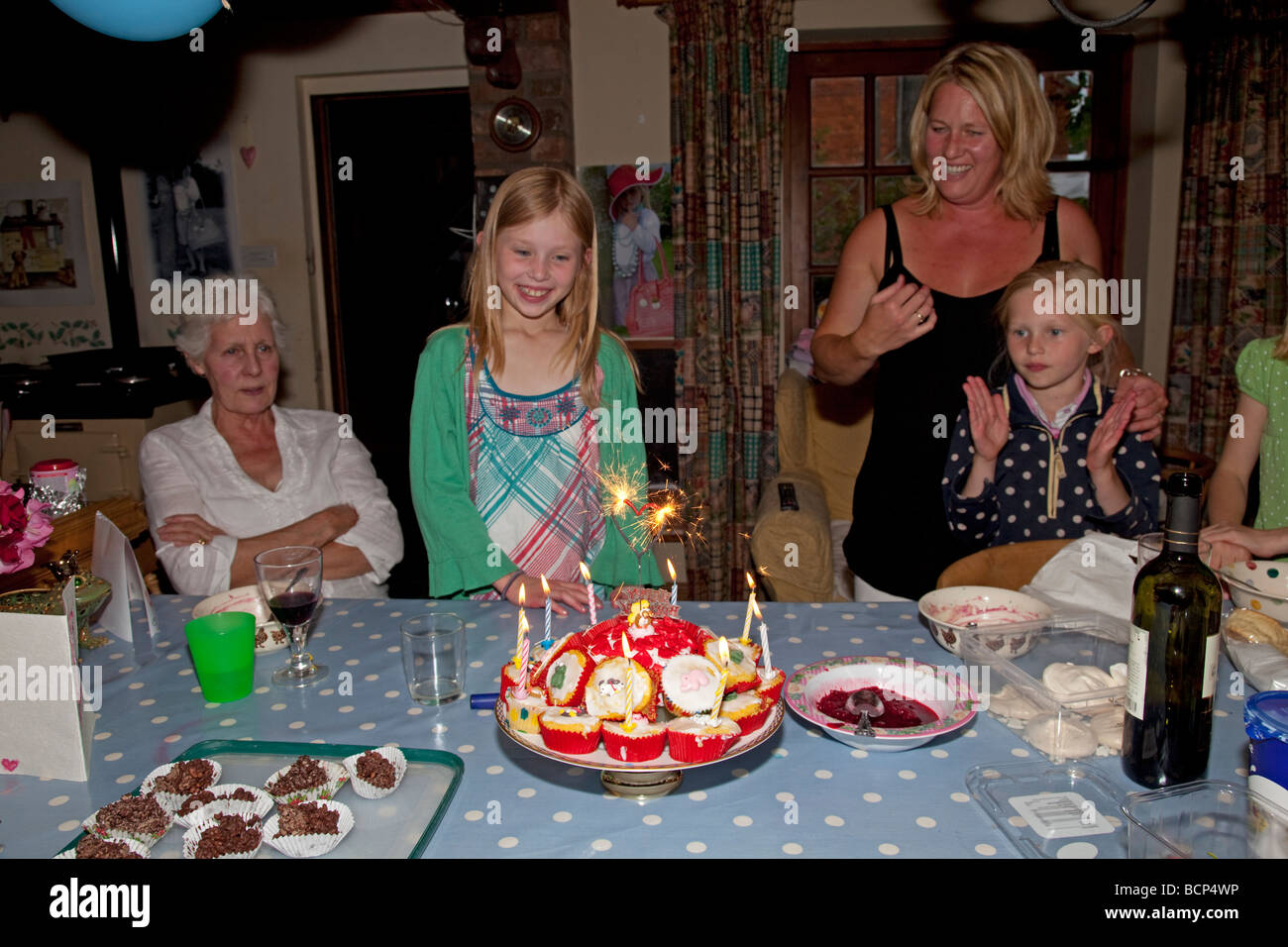 Neuf ans, fille avec des sœurs mère et grand-mère d'admirer le gâteau d'anniversaire Cotswolds UK Banque D'Images