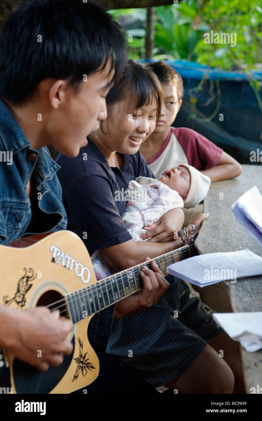 Une jeune famille asiatique chanter ensemble et à jouer de la guitare dans un village des tribus des collines du nord de la Thaïlande Banque D'Images