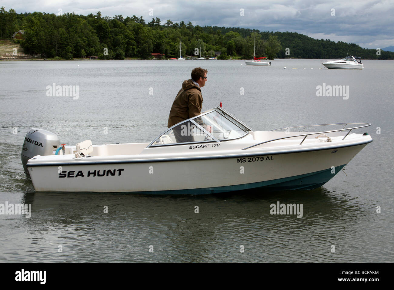 Un jeune homme sortir son bateau à moteur runabout de 17 pieds. La scène est le lac Champlain avec les montagnes Vertes du Vermont. Banque D'Images