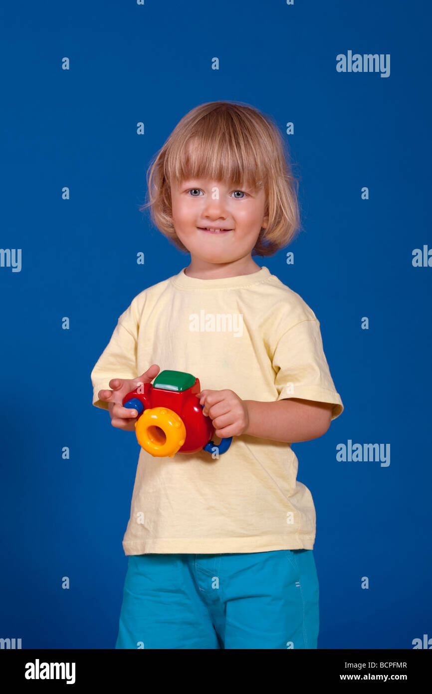 Portrait d'un garçon enjoué avec un appareil photo en plastique coloré Banque D'Images