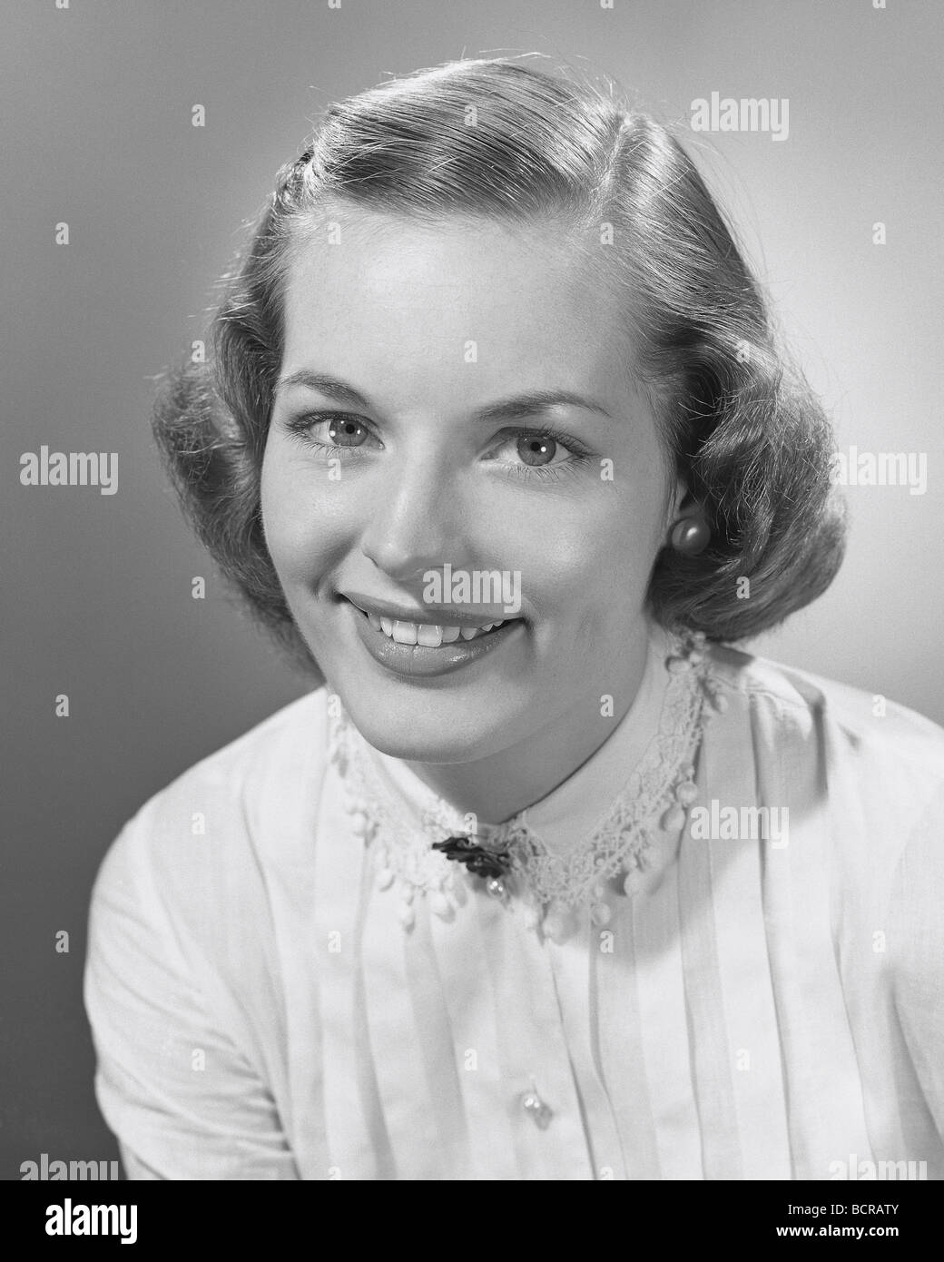 Portrait of young woman smiling, studio shot Banque D'Images