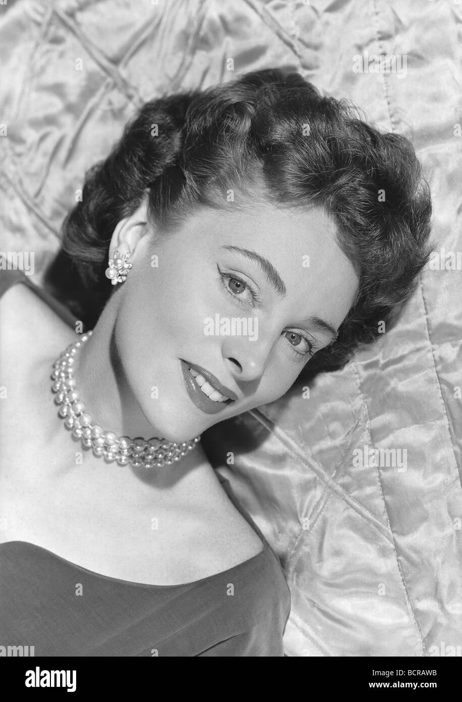 Portrait of young woman lying on bed, studio shot Banque D'Images