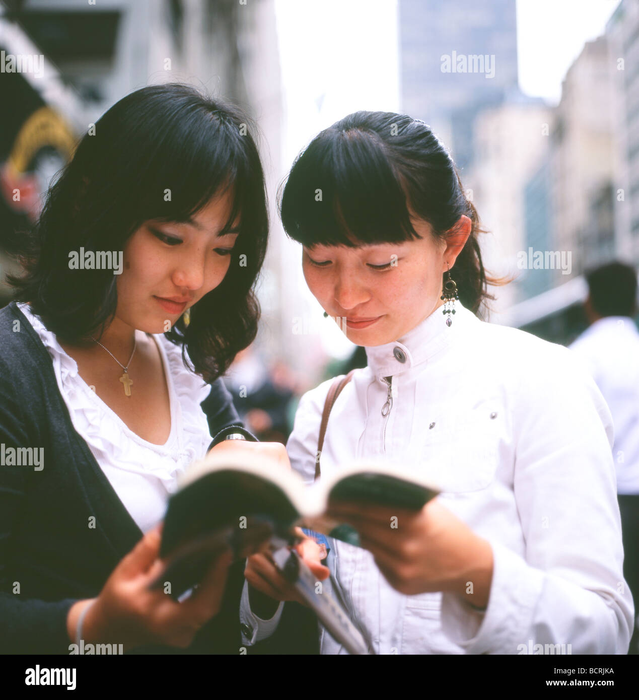 Les jeunes femmes asiatiques les touristes à la recherche d'un guide et carte de New York sur la 5e Avenue, New York City NY USA Banque D'Images