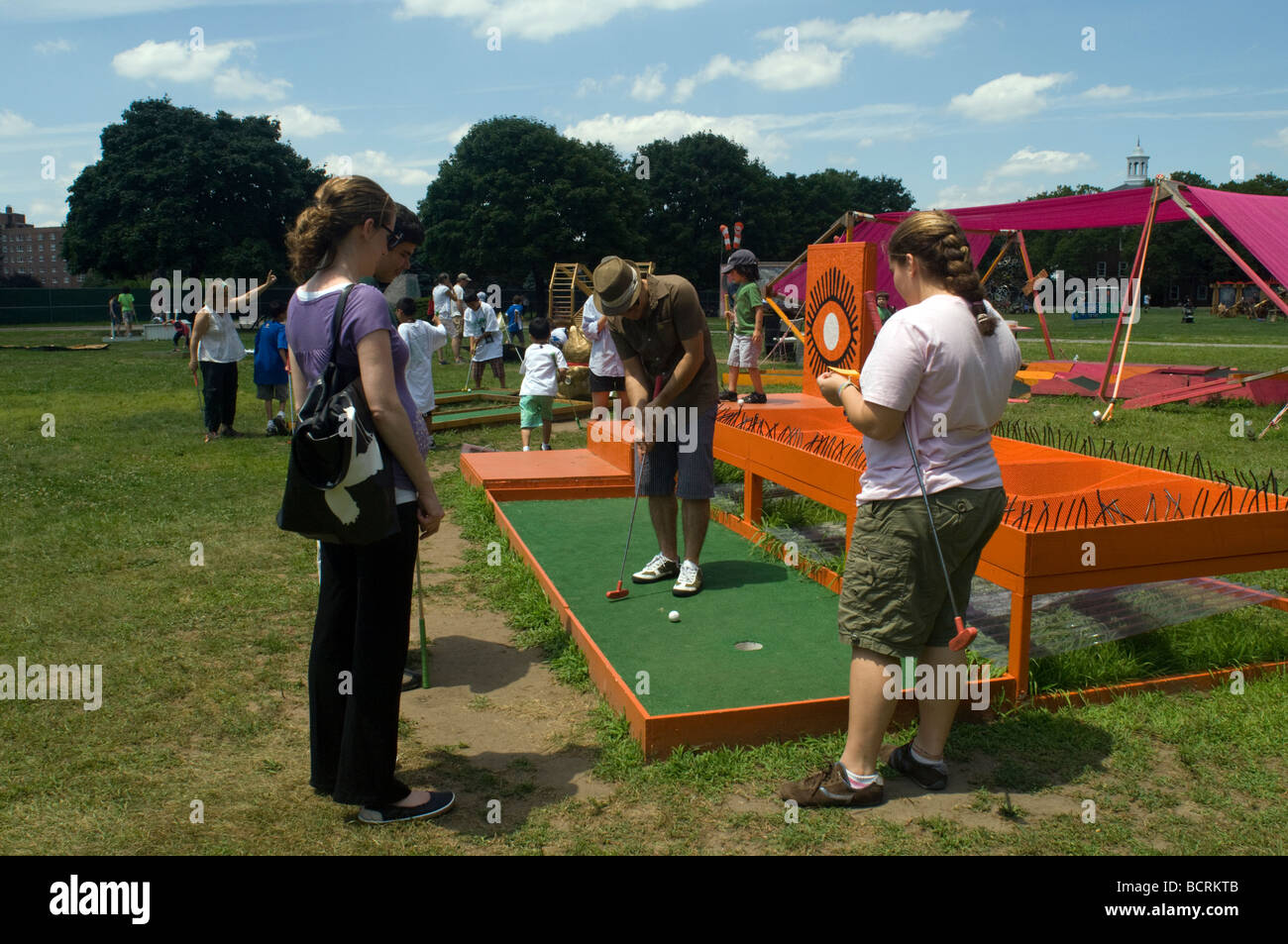 Les visiteurs de l'Île du gouverneur historique dans le port de New York jouer au golf miniature à la ville de rêves exposition d'art. Banque D'Images