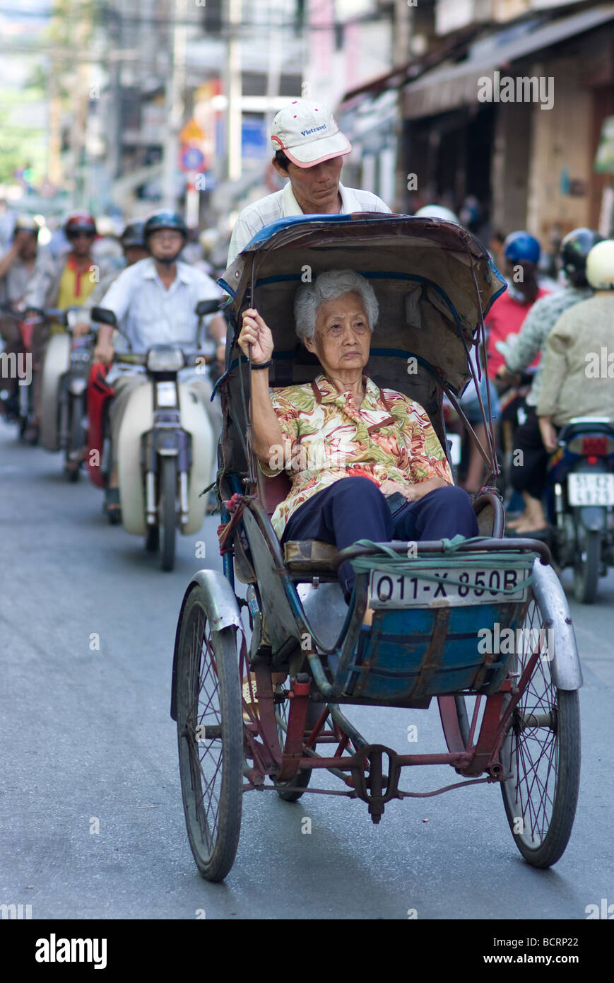 Personnes âgées femme chinoise d'être transportée avec un cyclo in Hoc Lac street Cho Lon le Chinatown de Ho Chi Minh City Vietnam Banque D'Images