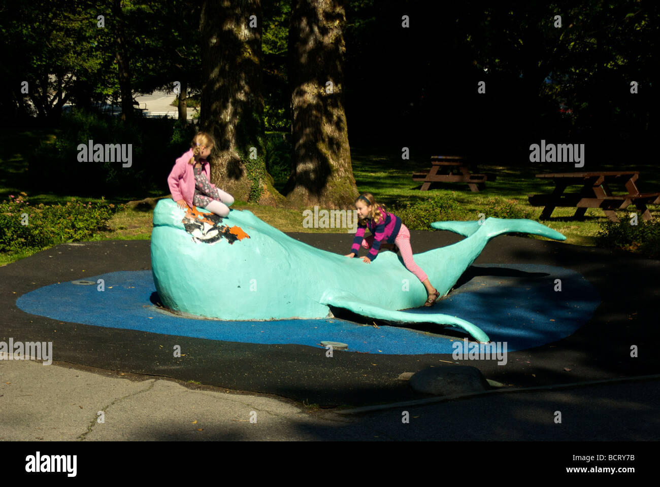 Deux jeunes filles faisant glisser et jouer sur l'aire de jeux pour enfants dans la sculpture de baleine Banque D'Images