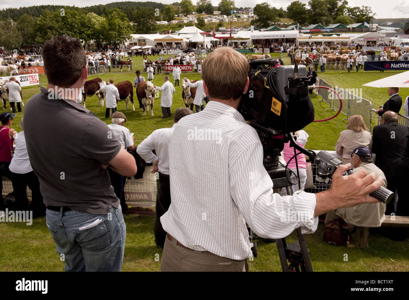 Cameraman vidéo numérique l'équipe du film et l'on en juge d'enregistrement dans le bétail sonne à un événement salon de l'agriculture en plein air pour la télévision. Banque D'Images