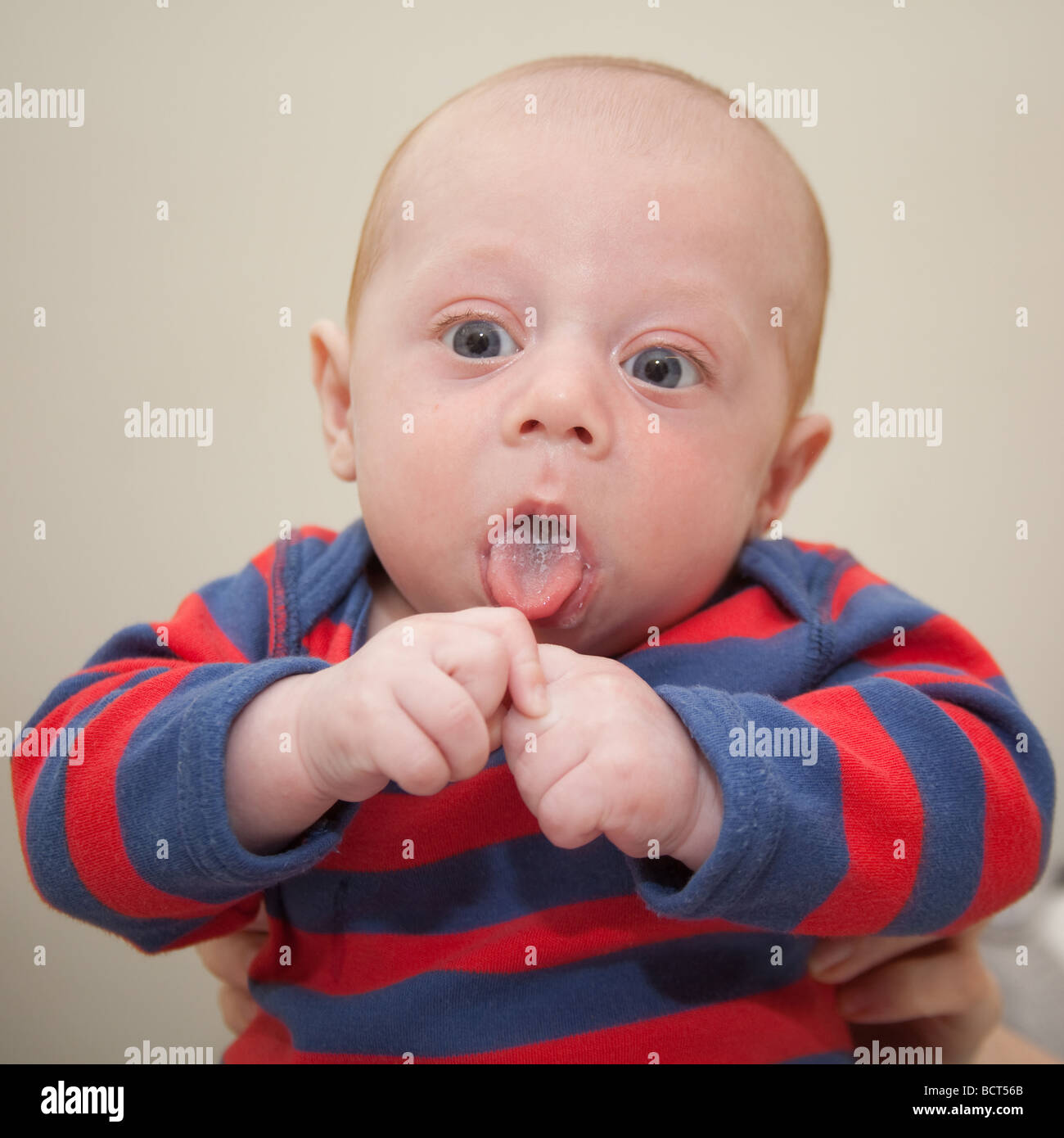 Deux mois bébé garçon vêtu d'un costume rayé bleu et rouge, Londres, Angleterre. Banque D'Images