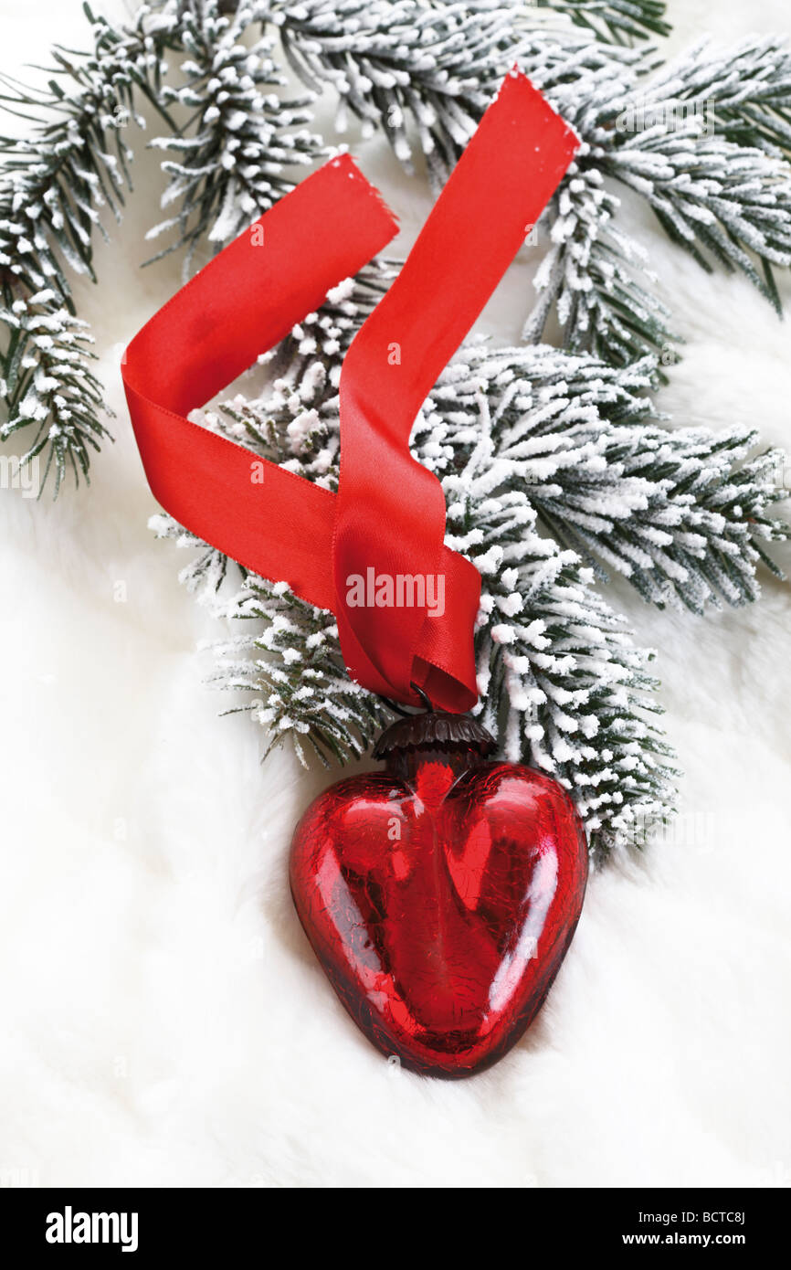 En forme de coeur rouge décoration de Noël sur la couverture de fourrure avec des branches de sapin Banque D'Images