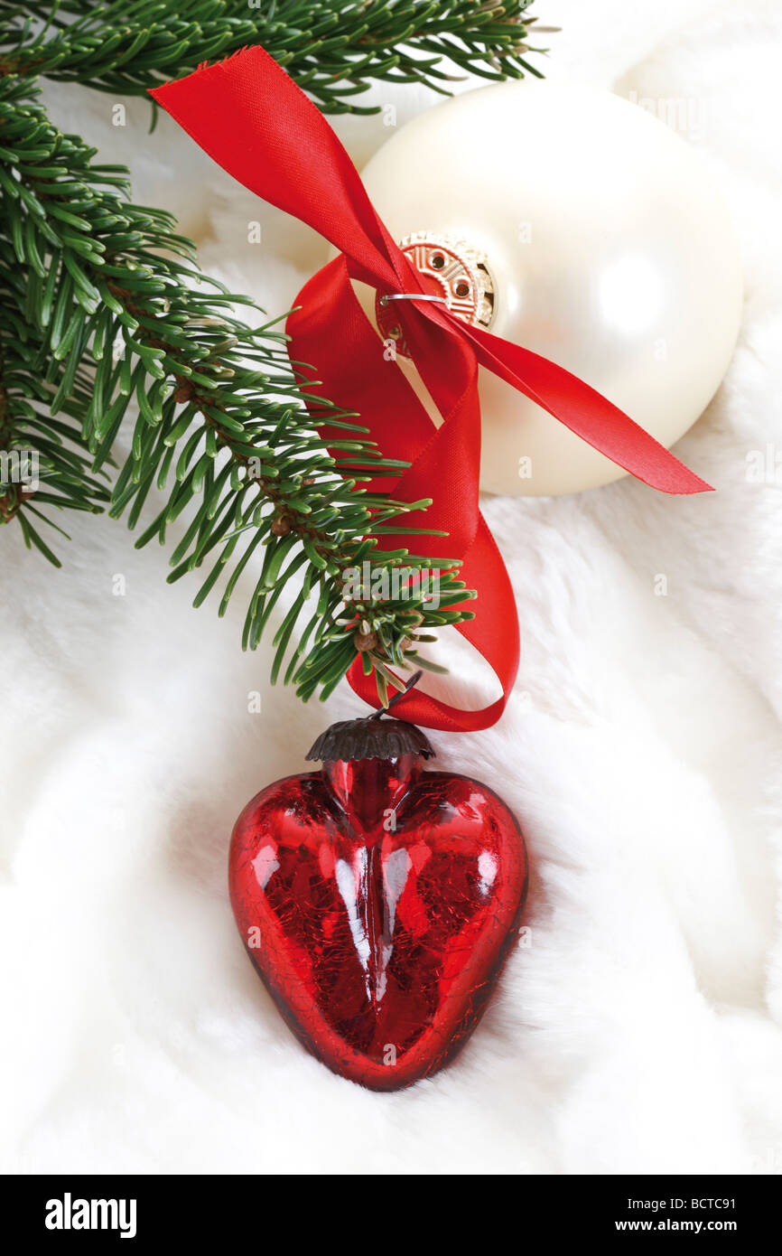 En forme de coeur rouge et argent décoration de Noël Boule de Noël avec des branches de sapin sur une couverture de fourrure Banque D'Images