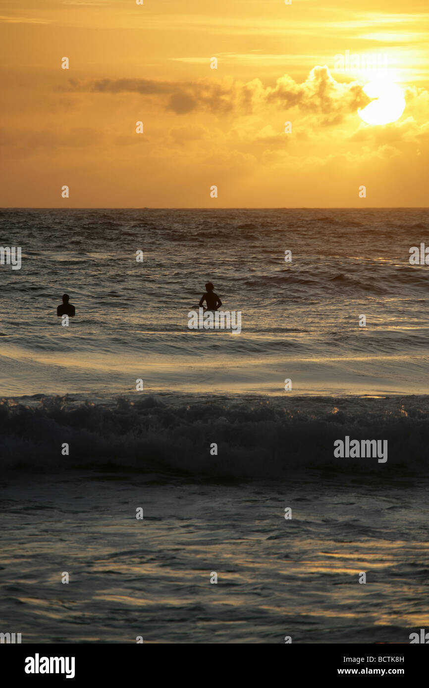 Domaine de Sennen, Angleterre. Voir la silhouette de surfeurs assis sur leurs planches de surf en attente d'une bonne vague de Gwenver Beach. Banque D'Images
