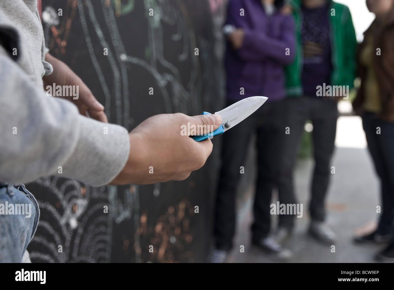 Adolescent menaçant un groupe avec un couteau Banque D'Images