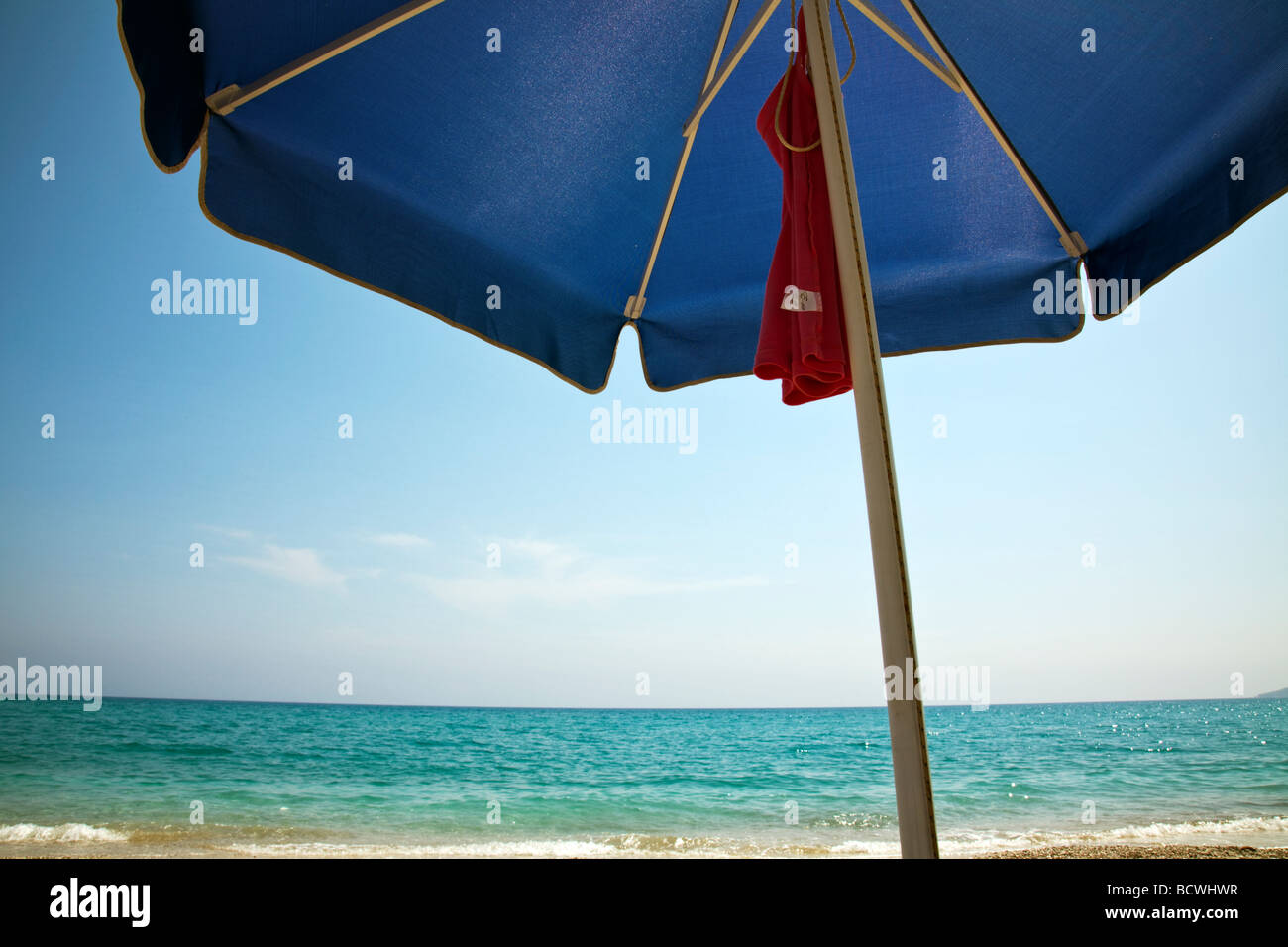 Farniente sur une plage à Céphalonie, île grecque au soleil, parasol à la prête, sable, ciel bleu sous un parasol Banque D'Images