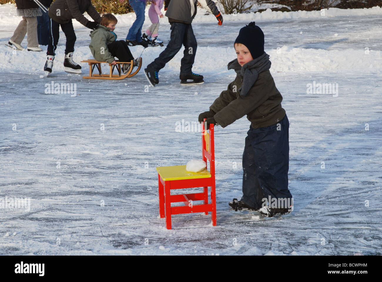 Petit enfant pratiquant avec chaise sur glace naturelle Banque D'Images