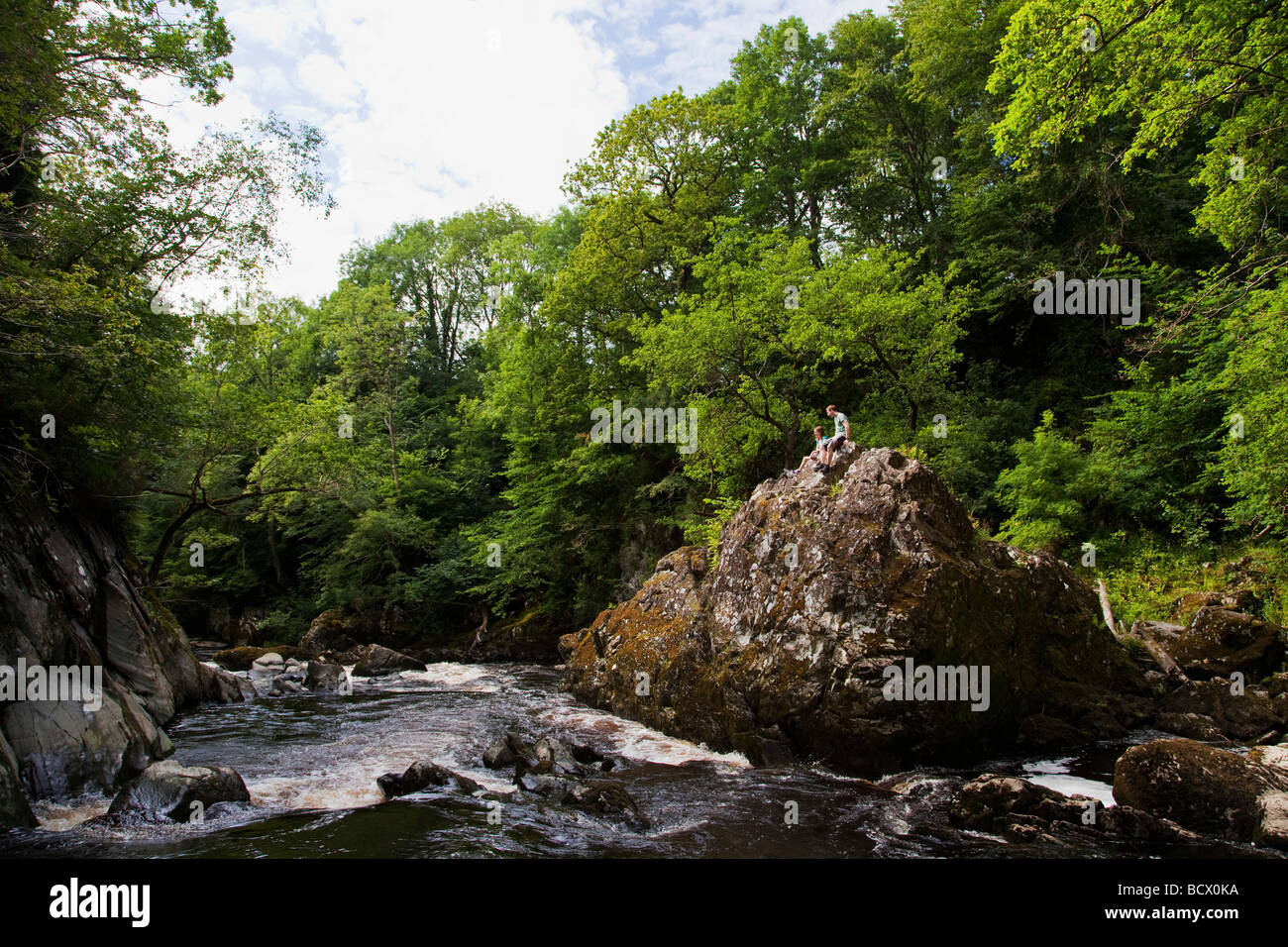 Young couple sitting on rock Gorge Fairy Glen en été la rivière Conwy soleil juillet près de Betws-Y-Coed Cymru, Nord du Pays de Galles UK Banque D'Images