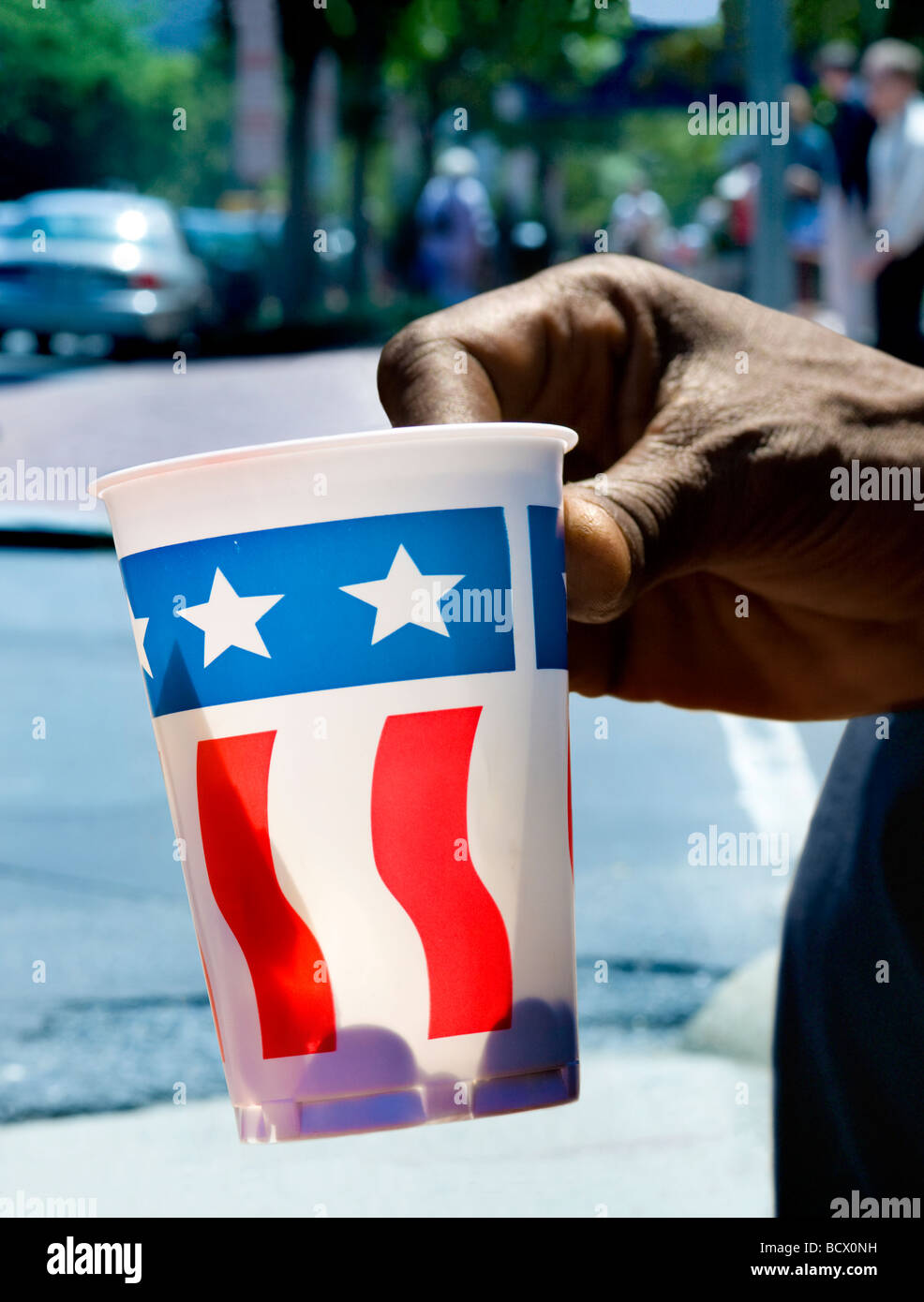 Main de personne sans-abri, la tasse de papier avec nous d'un drapeau à la mendicité pour changer sur Pennsylvania Avenue, Washington DC. Banque D'Images