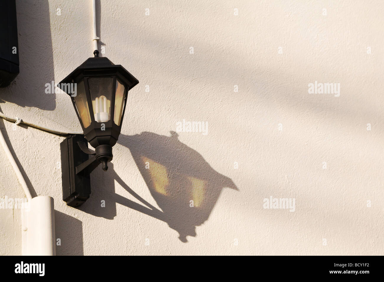 Un style traditionnel fixée au mur extérieur de longue durée, avec l'ampoule basse consommation, jette une ombre sur le mur. UK. Banque D'Images