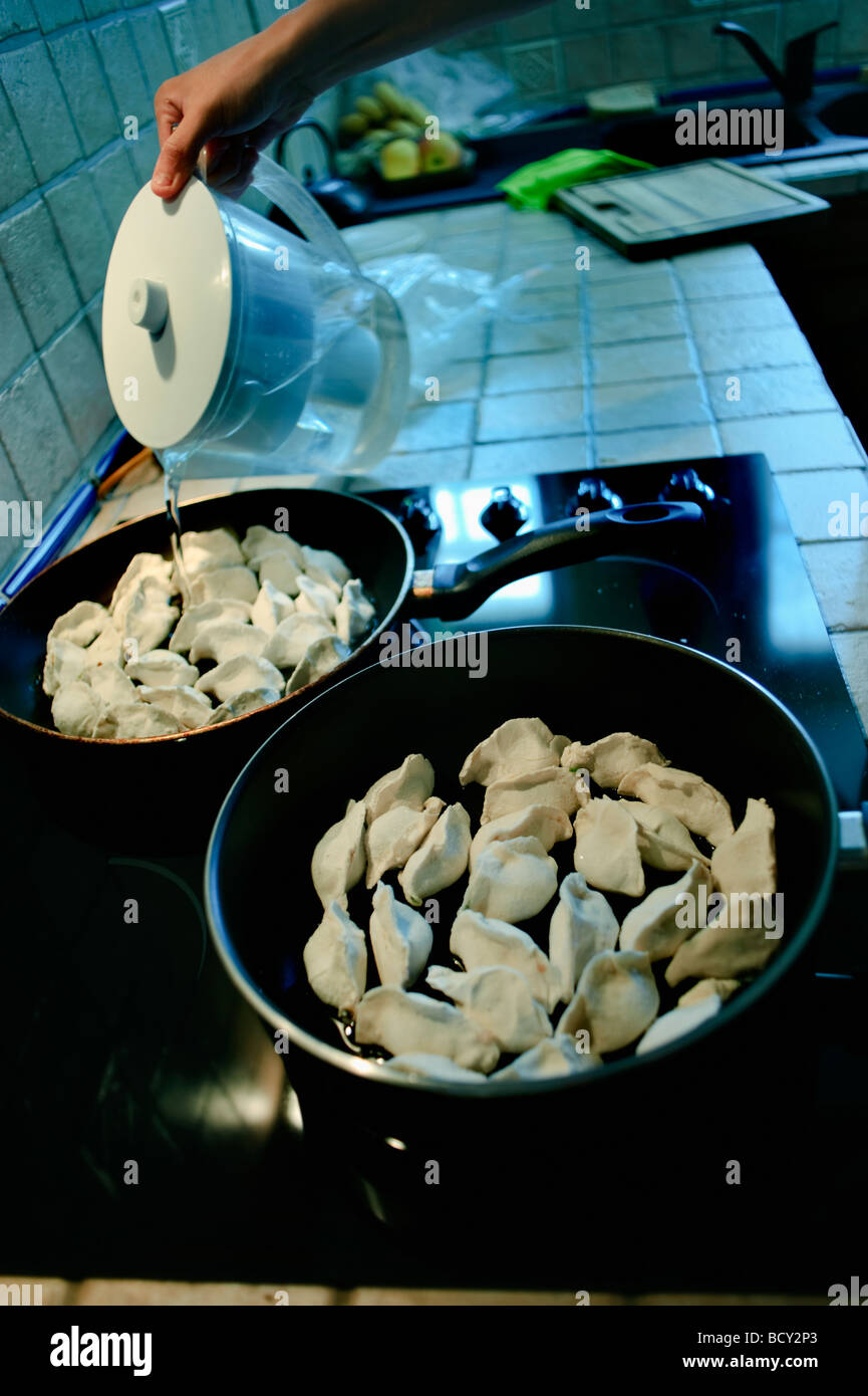 Cuisine chinoise « boulettes chinoises » dans la cuisine, détail « verser de l'eau » dans la poêle, manger à la maison, dîner chinois Banque D'Images