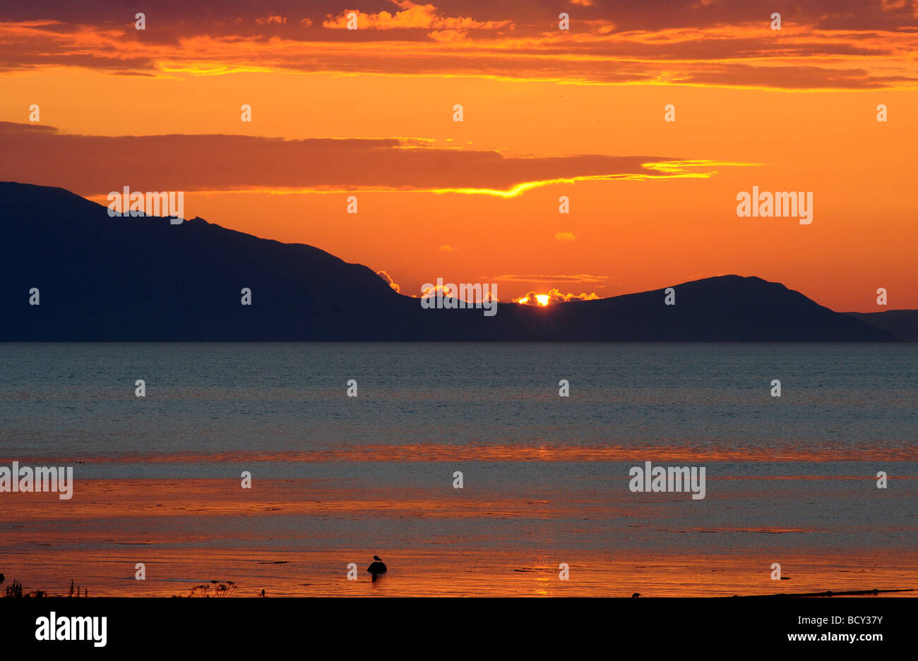 Le soleil se couche derrière l'île d'Arran, à la recherche de la côte d'Ayrshire, en Écosse. Banque D'Images