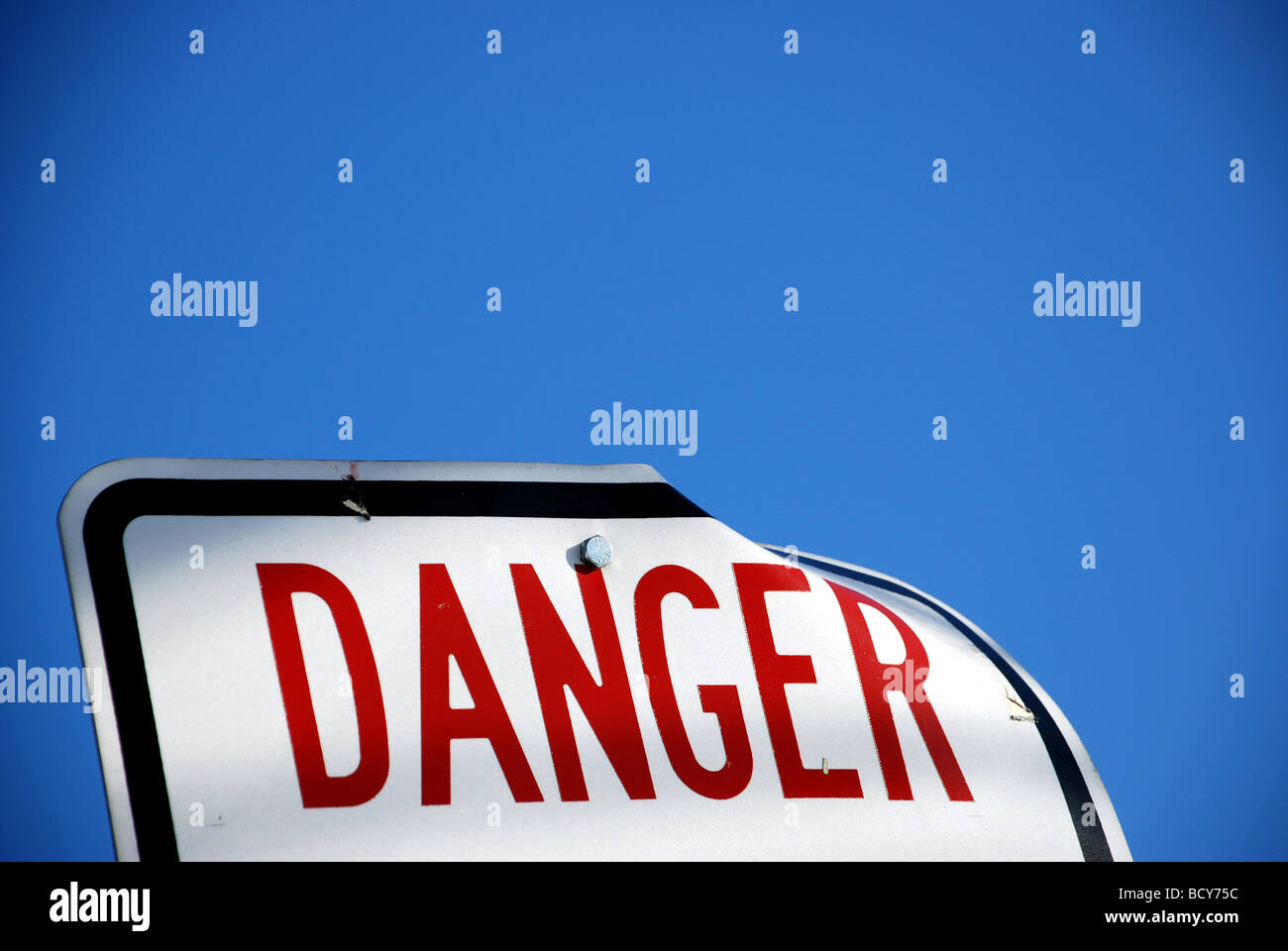 Panneau blanc avec rouge type disant danger avec ciel bleu en arrière-plan Banque D'Images