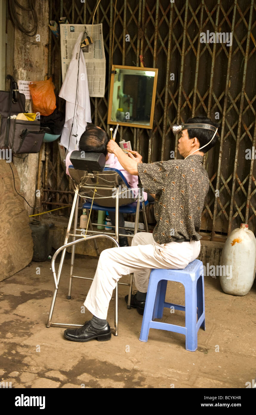 La boutique de plein air coiffure coiffure est le nettoyage de l'oreille du client.,Vieille Ville, Hanoi, Vietnam, Banque D'Images