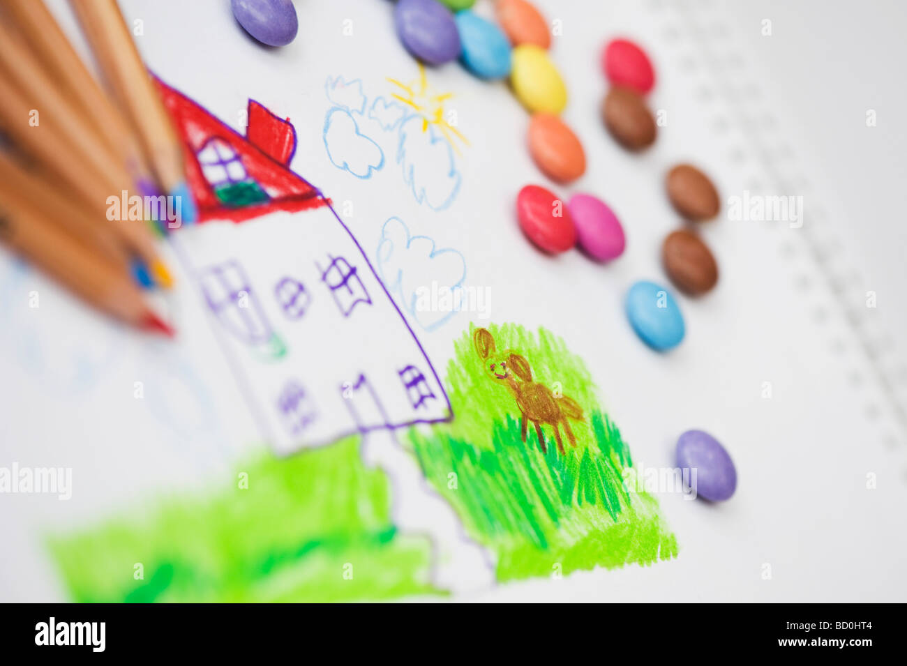 Dessin d'enfant d'une maison et le chien à l'aide de crayons entouré par smarties Banque D'Images