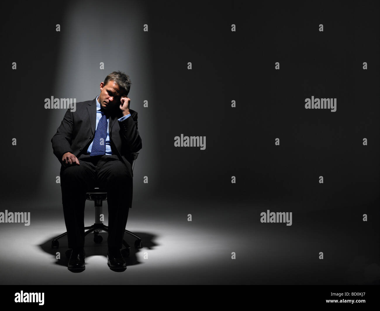 Businessman Sitting in Spotlight Banque D'Images