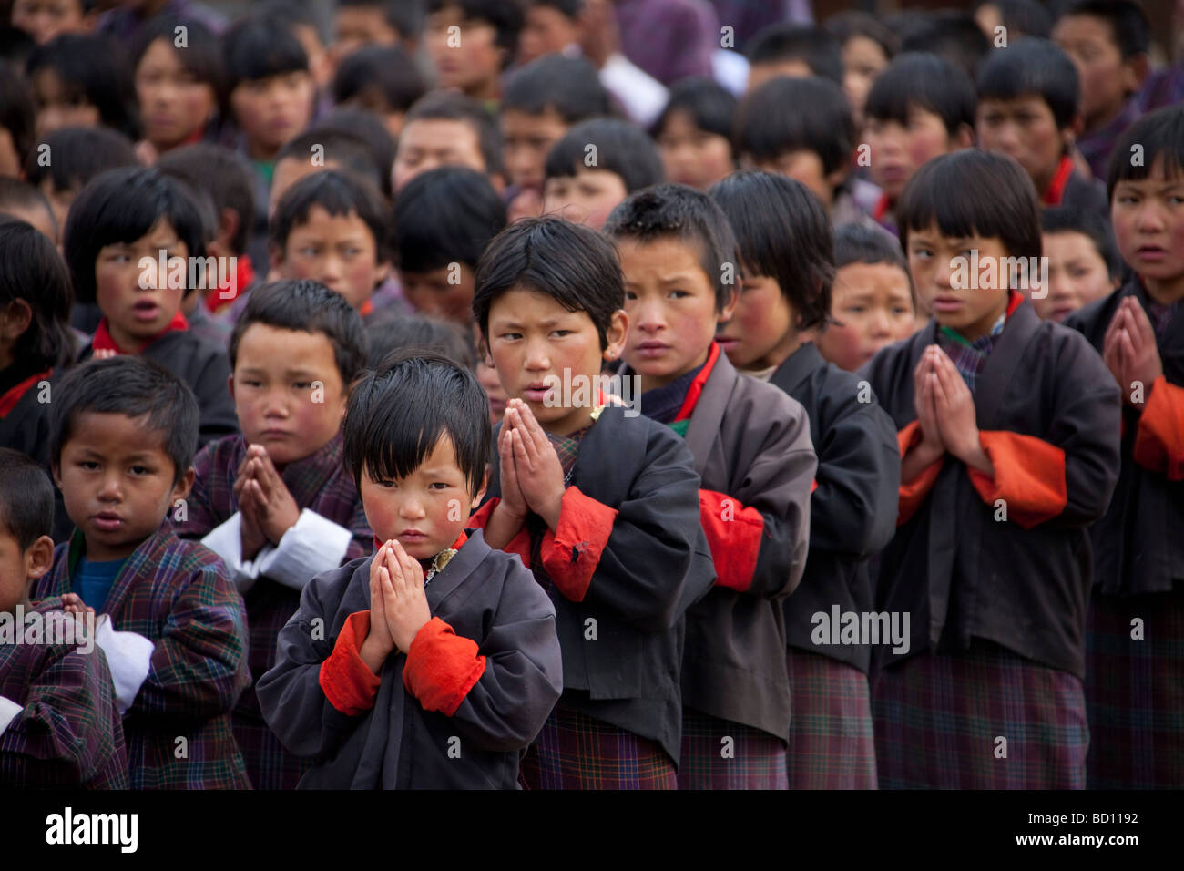 Groupe de jeunes écoliers en uniforme des manches manches rouge à prier dans l'assemblée d'école 91948 Bhutan-Wangdue Banque D'Images