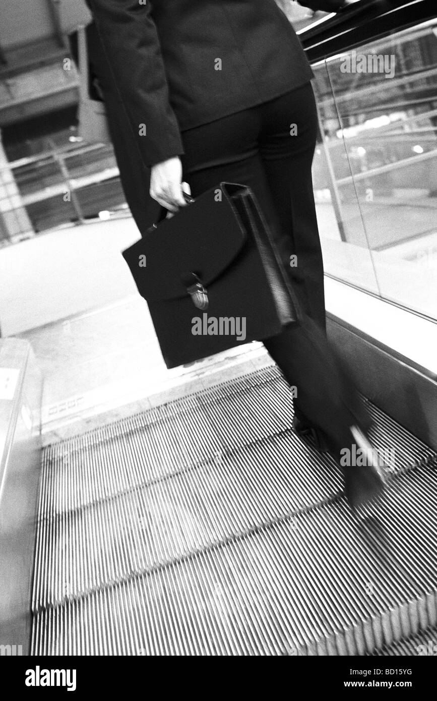 Businesswoman ascending escalator, vue arrière Banque D'Images