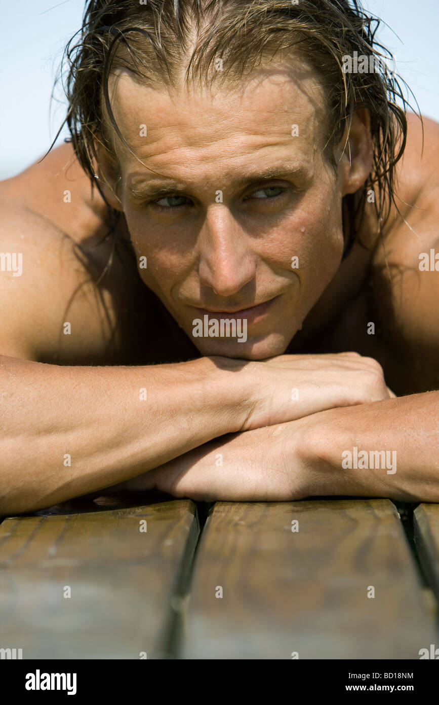 Man resting head on arms sur le côté de la piscine Banque D'Images