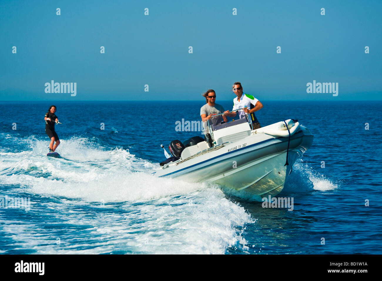Fille sur un wakeboard derrière un bateau gonflable Banque D'Images