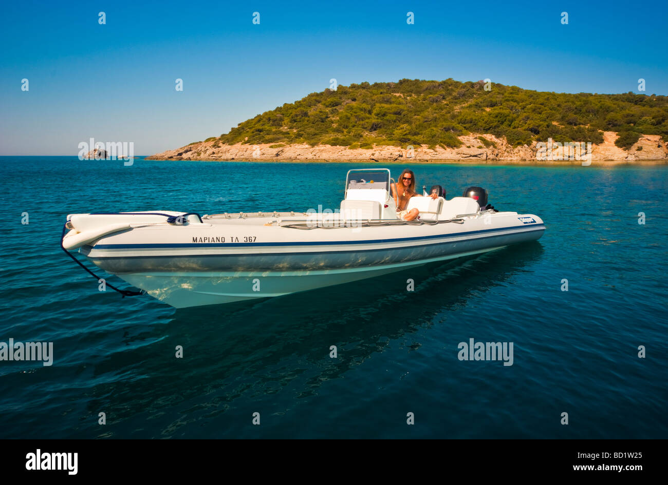 L'homme à un gros bateau gonflable sur l'océan en face d'une île grecque Banque D'Images