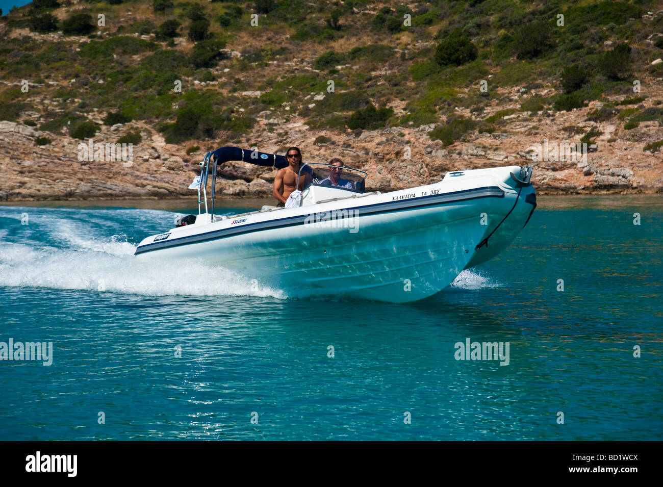 Les hommes en blanc rapide bateau gonflable à proximité du littoral Banque D'Images