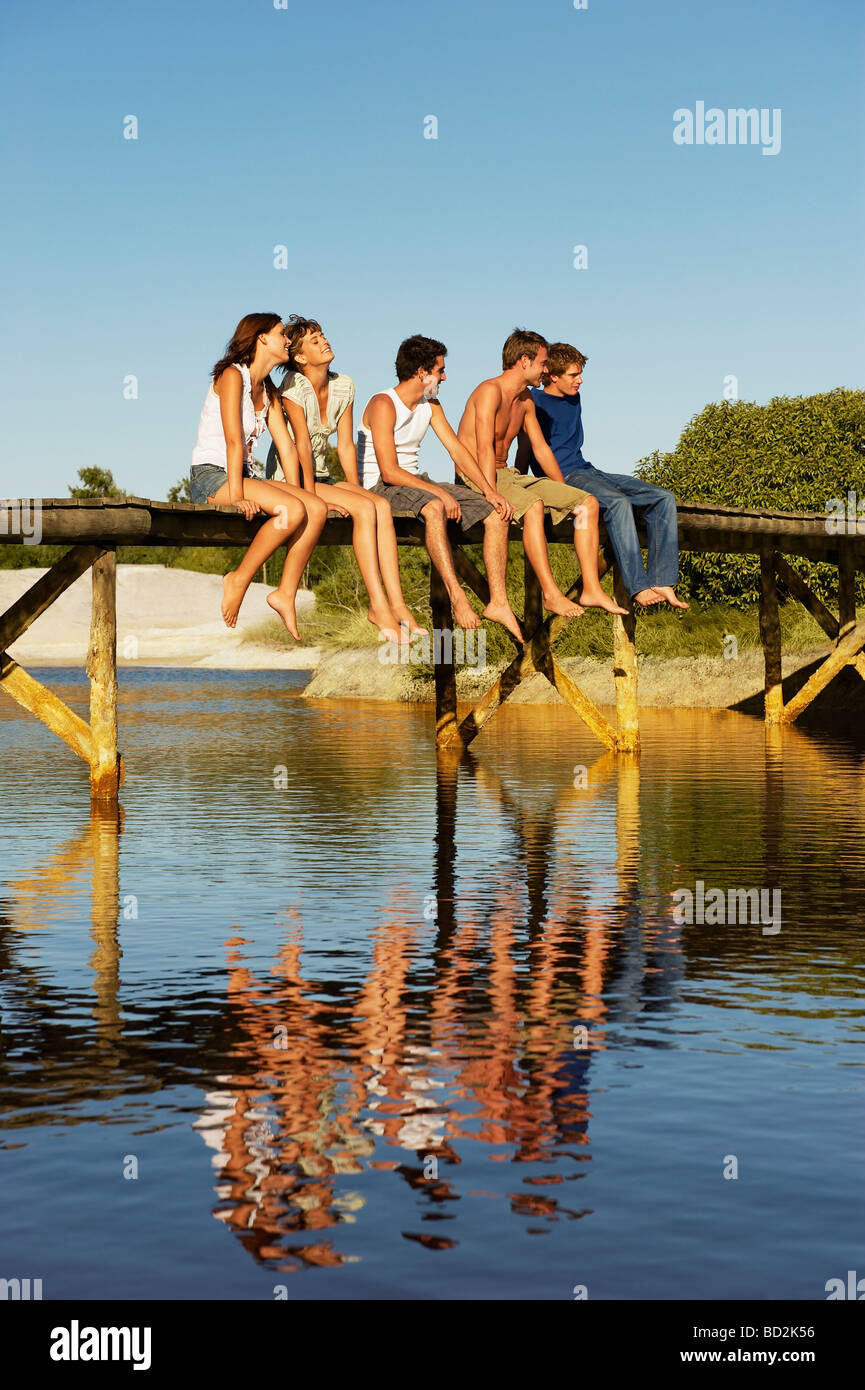Groupe de jeunes sitting on jetty Banque D'Images
