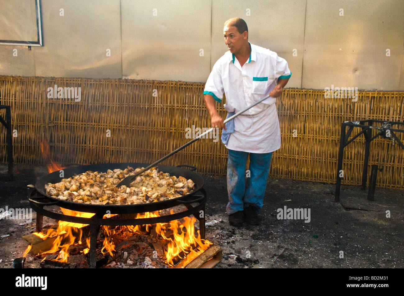 Cuire en remuant la Paella comme il cuit sur un feu ouvert sur la Playa la plage de Burriana, Nerja, Costa del Sol en Espagne Banque D'Images