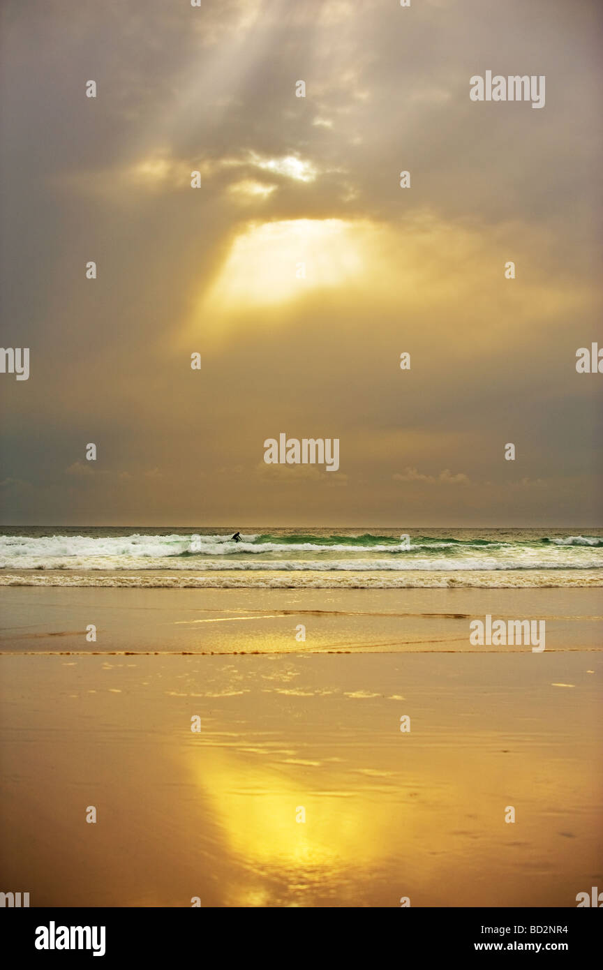 Lone surfer à Gwithian Towans beach au coucher du soleil. Banque D'Images