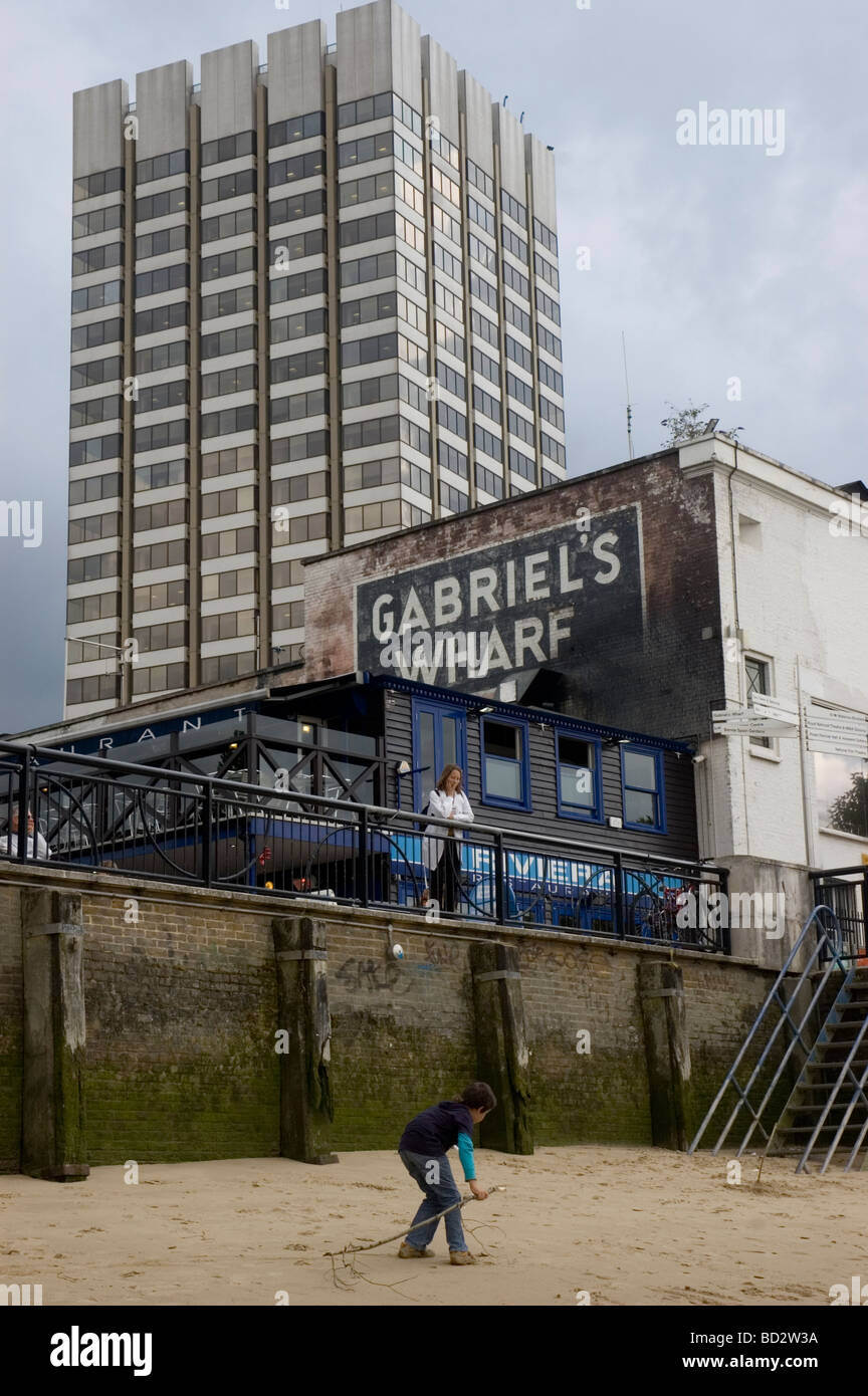 Un garçon joue sur la plage de la Tamise à marée basse avec Gabriels Wharf et Kent House (QG d'ITV) dans l'arrière-plan Banque D'Images