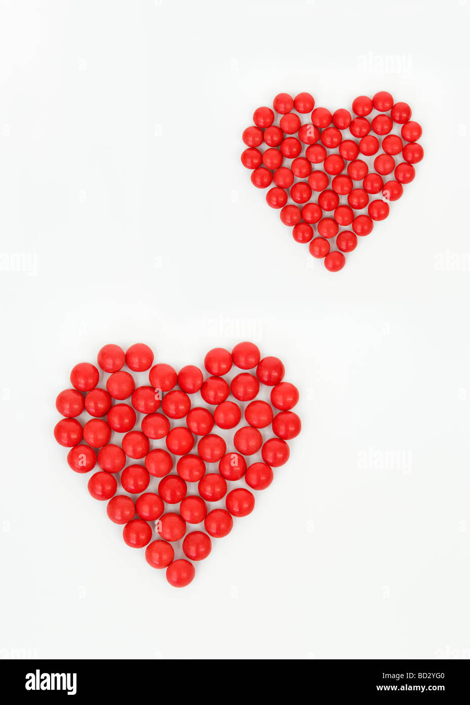 La vie toujours tourné artistique de l'ensemble des bonbons rouges en deux formes coeur prises sur un fond blanc. Banque D'Images