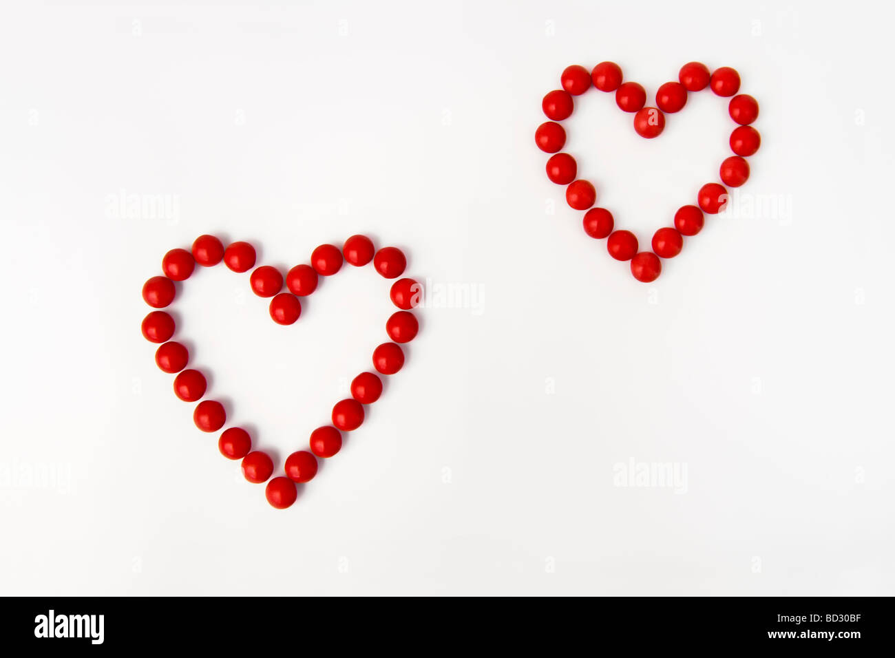 La vie toujours tourné artistique de l'ensemble des bonbons rouges en deux formes coeur prises sur un fond blanc. Banque D'Images