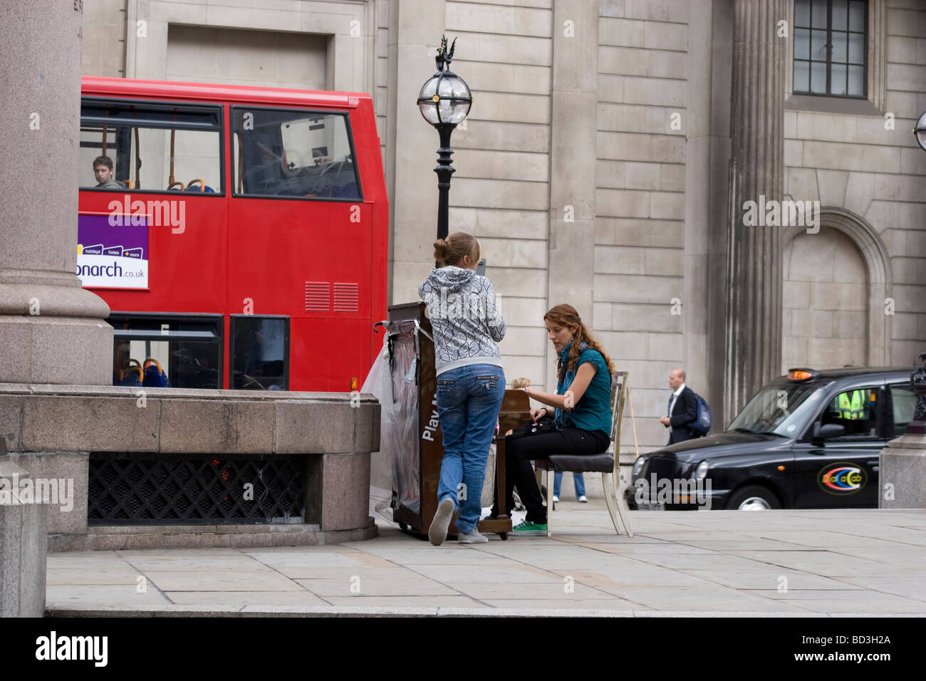 Les gens jouent sur l'un des 30 pianos placés dans des espaces publics dans le cadre d'une installation artistique, à l'extérieur de la Bank of England Threadneedle Street, Londres, Royaume-Uni. Banque D'Images