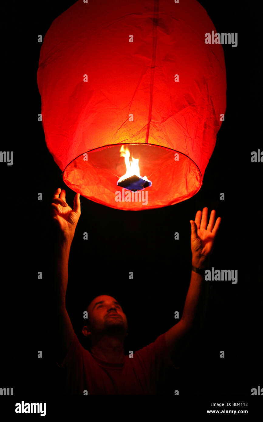 L'homme le lancement d'une lanterne ciel dans le ciel de nuit Banque D'Images