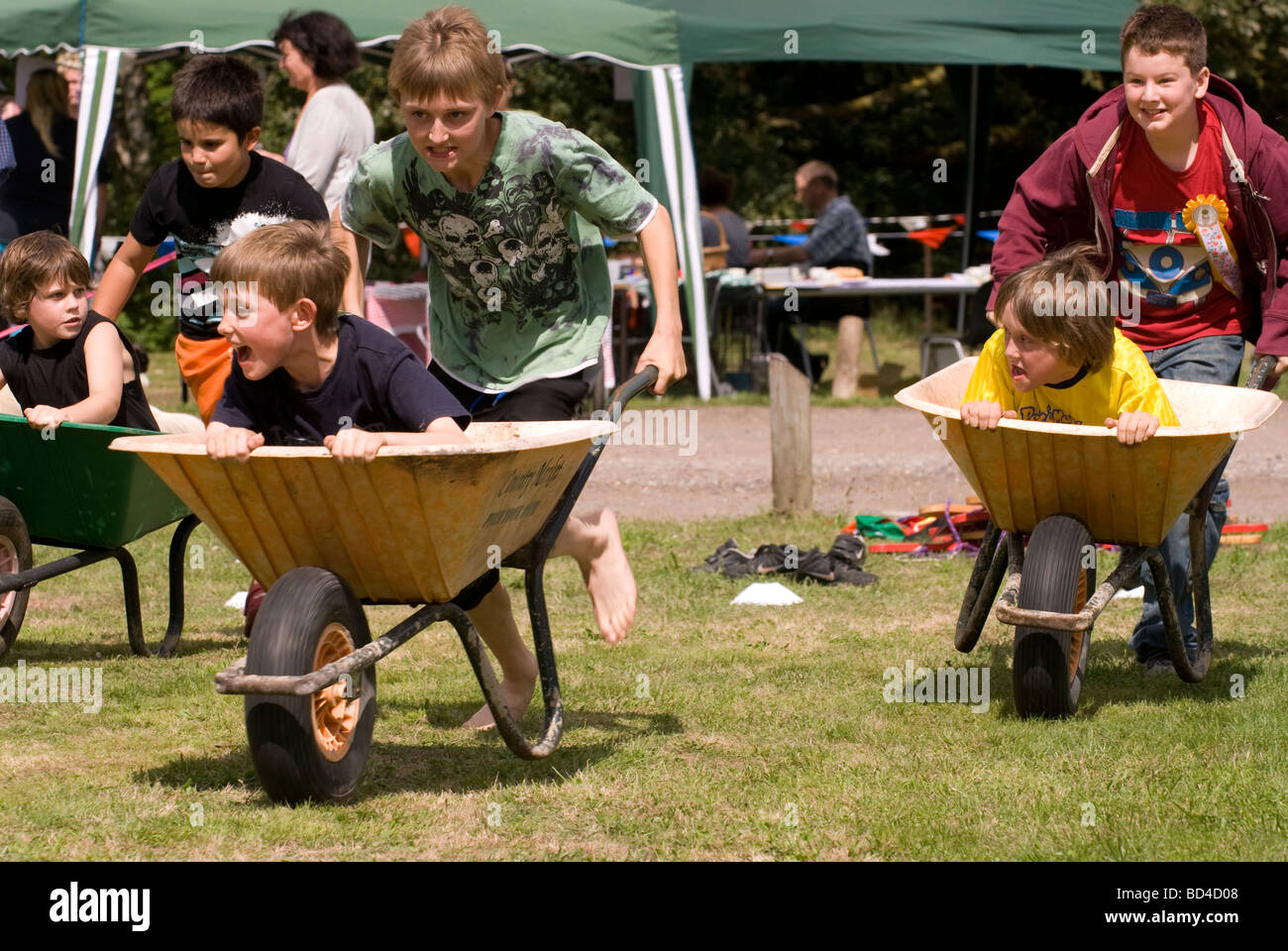 Les enfants qui prennent part à la course de brouettes à Oakhanger Village Show, Hampshire UK. Banque D'Images