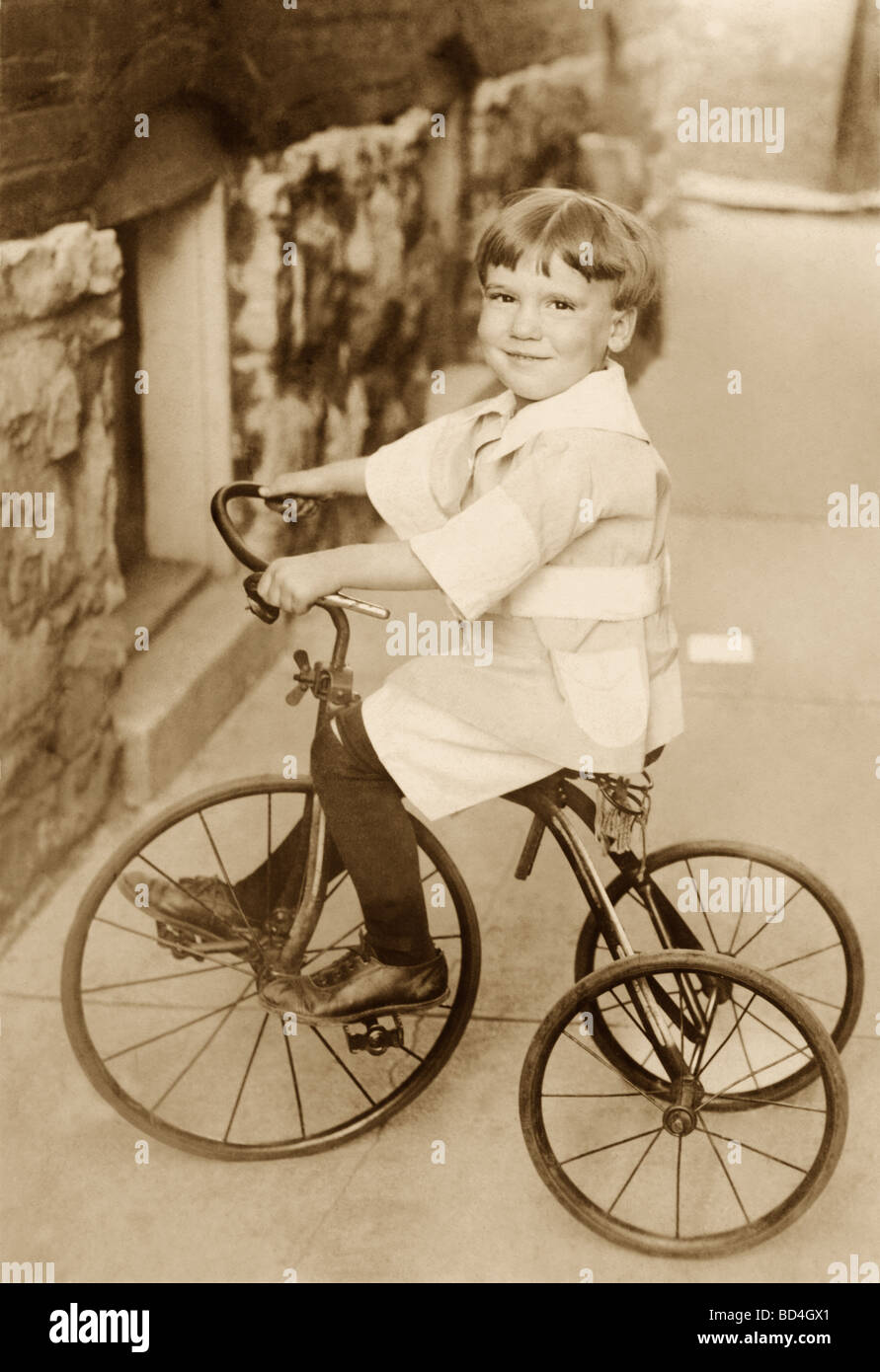 Little Boy Riding Tricycle sur trottoir Banque D'Images
