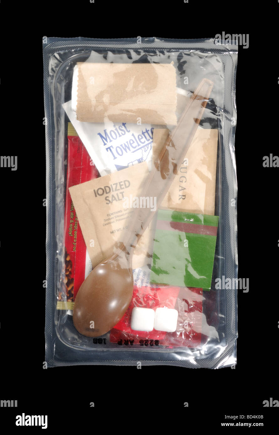Une ration alimentaire militaire de paquets avec des ustensiles et des fournitures sur fond noir Banque D'Images