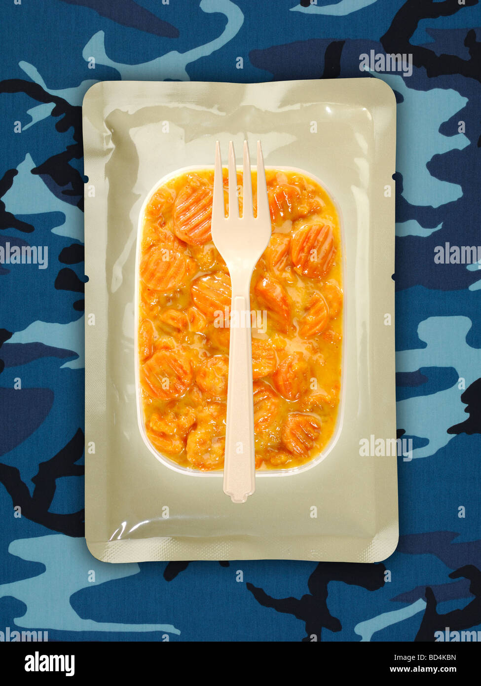 Une ration alimentaire militaire avec une fourche sur un fond bleu camouflage, carottes coupées en sauce Banque D'Images