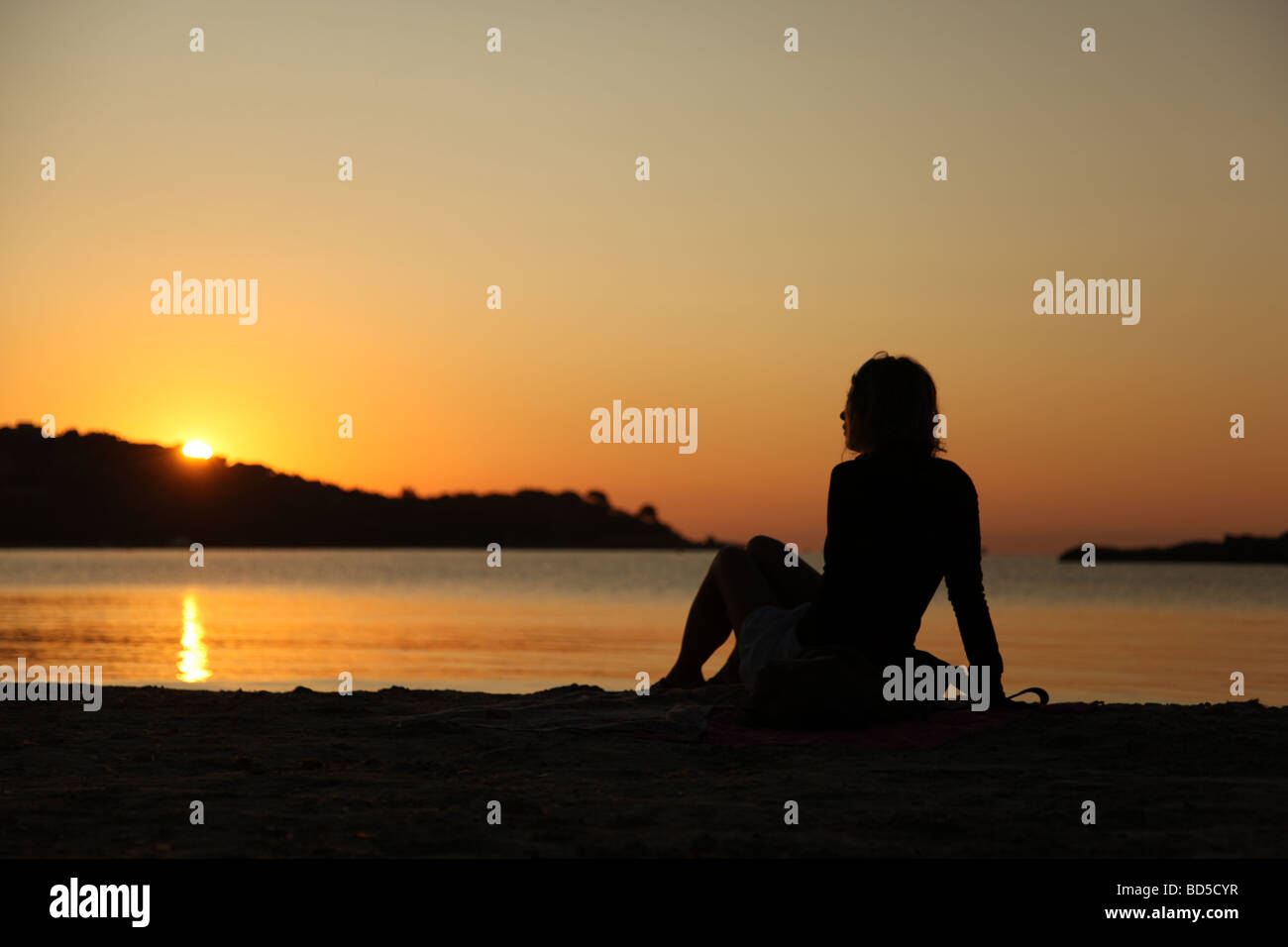 Silhouette d'une femme appréciant le lever du soleil sur la plage de Santa Giulia en Corse, France Banque D'Images