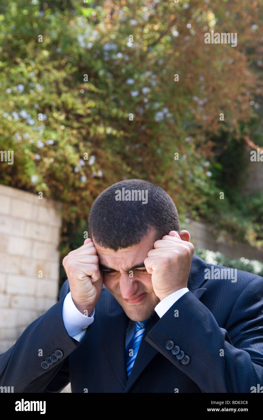 Business man head in hands outdoors Banque D'Images